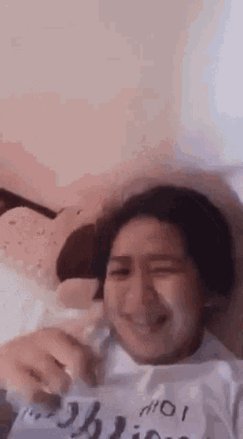 a woman is laying on a bed and smiling while wearing a white shirt .