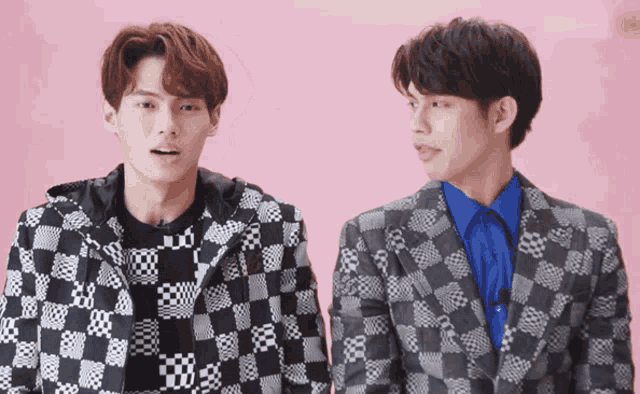 two men standing next to each other wearing plaid suits
