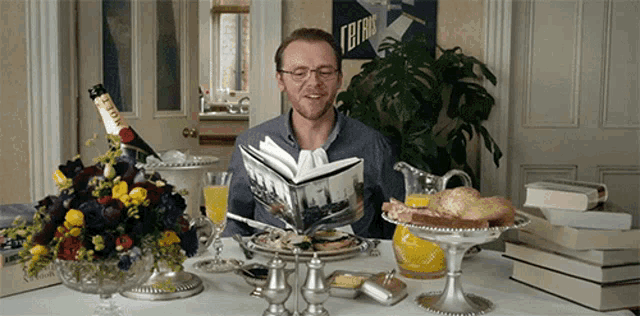 a man sits at a table reading a book with a bottle of moet champagne in the background