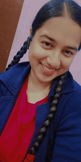a woman wearing a blue jacket and a red shirt is smiling for the camera