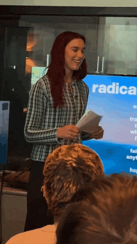 a woman is giving a presentation in front of a screen that says " radical "