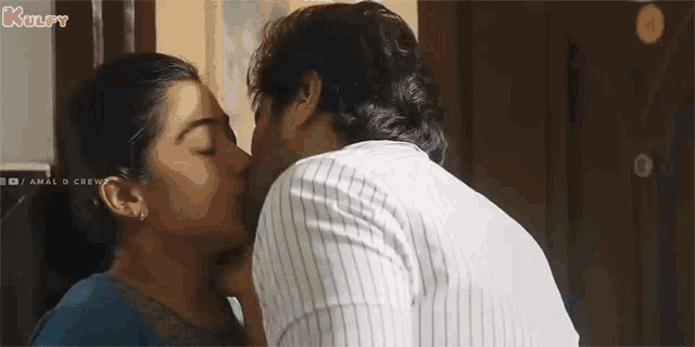 a man and a woman are kissing in front of a door in a room .