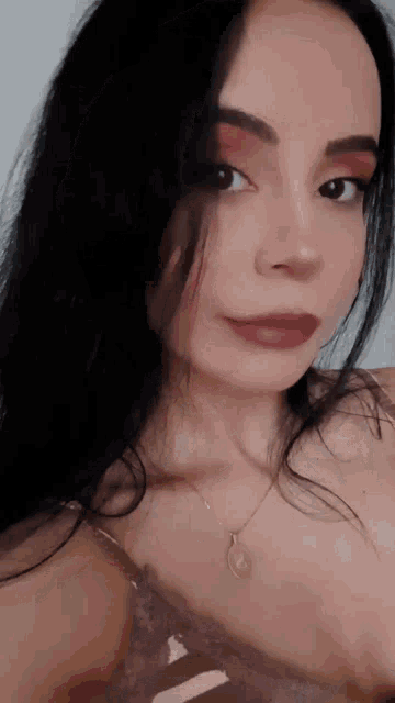 a woman with long black hair is wearing a necklace and a bra