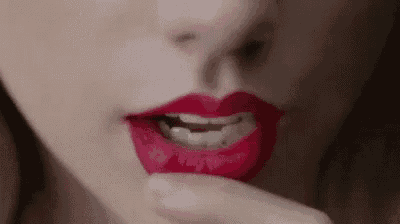 a close up of a woman 's mouth with red lipstick and a finger in her mouth .