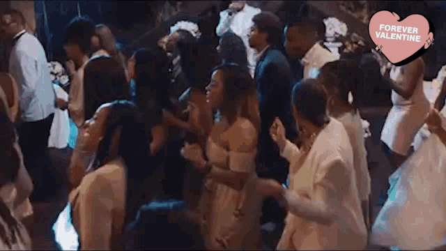 a large group of people are dancing on a dance floor at a wedding reception .