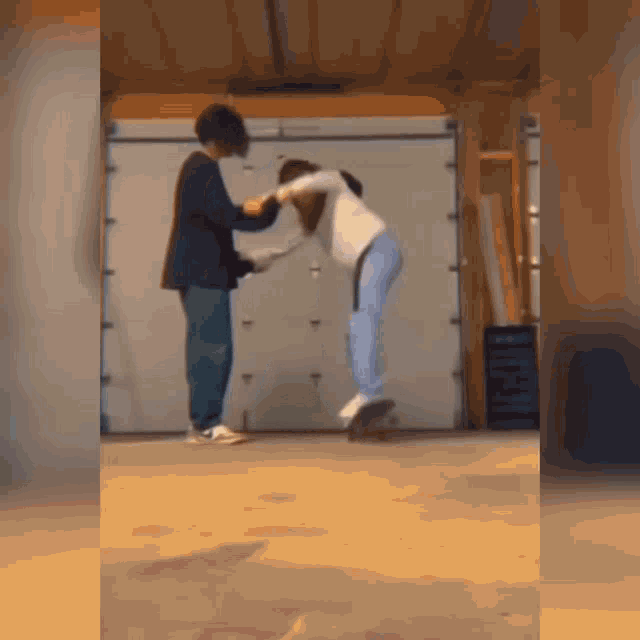 a man is standing next to a woman on a skateboard in a garage doorway .