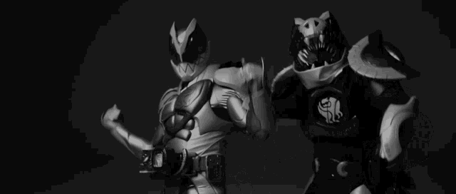 a black and white photo of two action figures flexing their arms