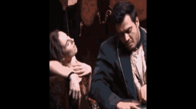 a man in a suit and tie is sitting next to a woman in a chair .