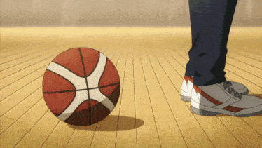 a person standing next to a basketball on a wood floor