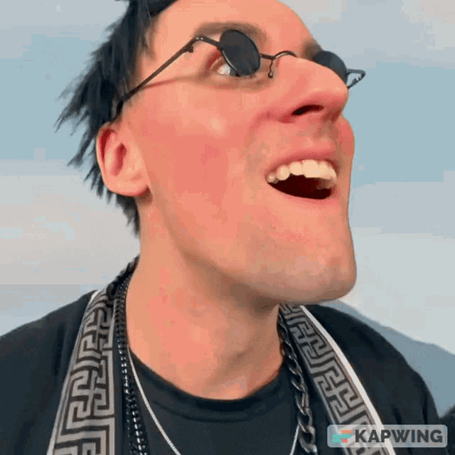 a man wearing sunglasses and a greek key scarf has kapwing written on the bottom right