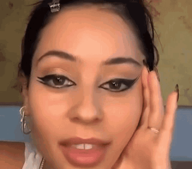 a close up of a woman 's face with a hand on her face .
