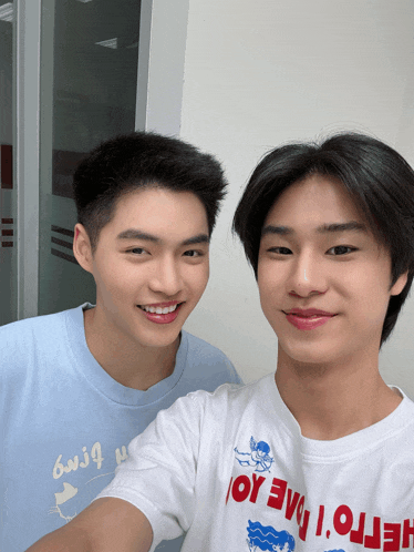 two young men are posing for a picture with one wearing a white shirt that says hello