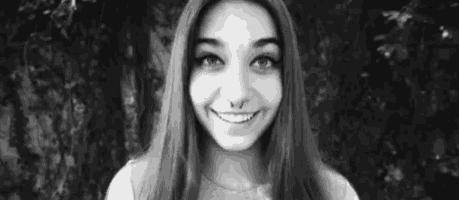 a black and white photo of a young woman with long hair smiling .