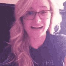 a close up of a woman wearing glasses and a purple shirt .