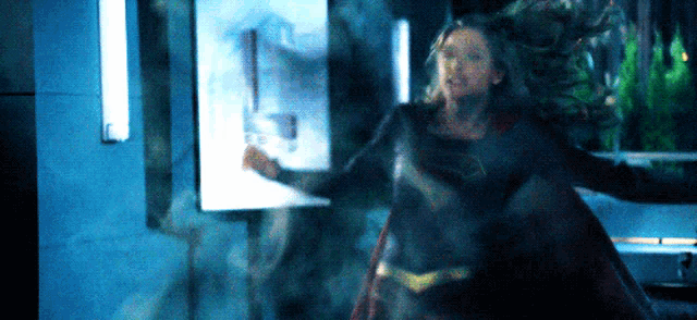 a woman in a superman costume is standing in a room .