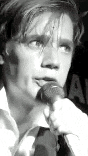 a black and white photo of a man holding a microphone in his hand .