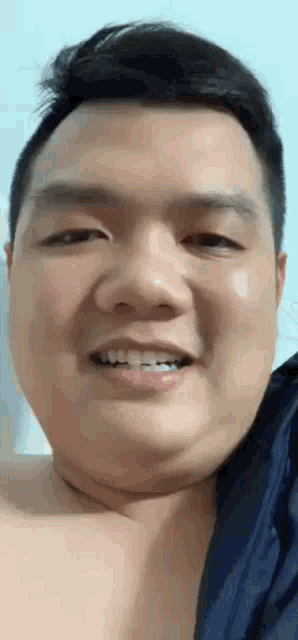 a close up of a man 's face with a blue shirt on smiling .