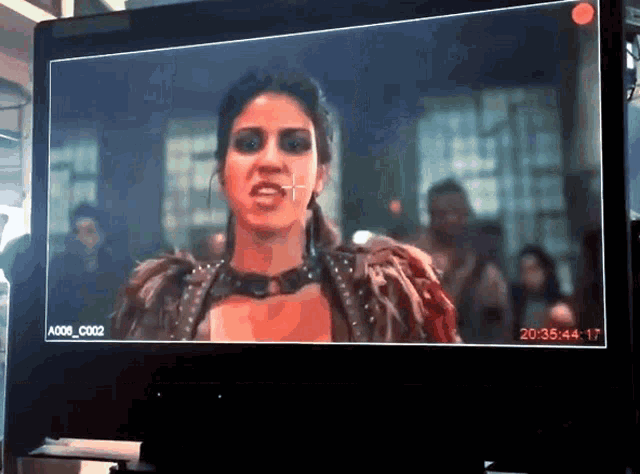 a screen shows a woman in a feathered outfit and says a006_c002