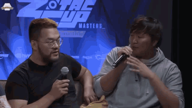 two men are sitting in front of a sign that says z tac up
