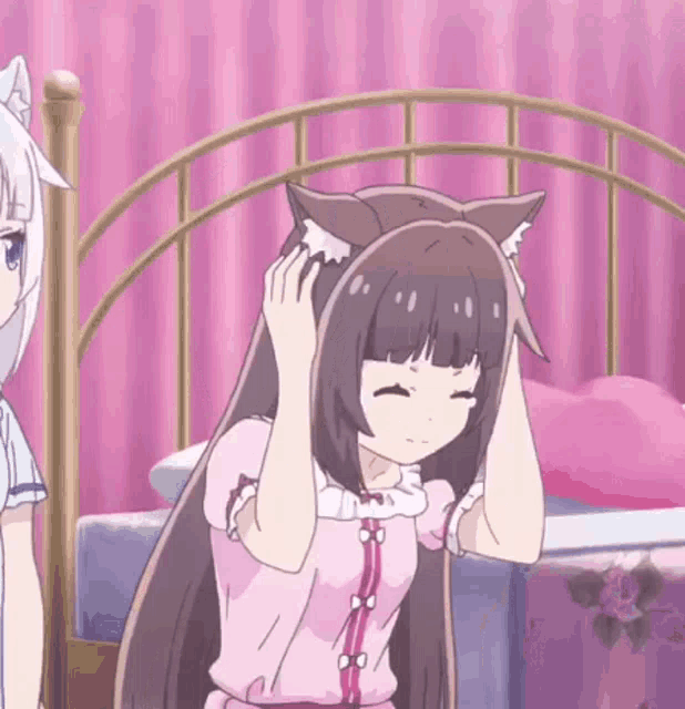 two anime girls are standing next to each other on a bed . one of the girls has cat ears on her head .