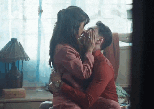 a man and woman are kissing on a bed .