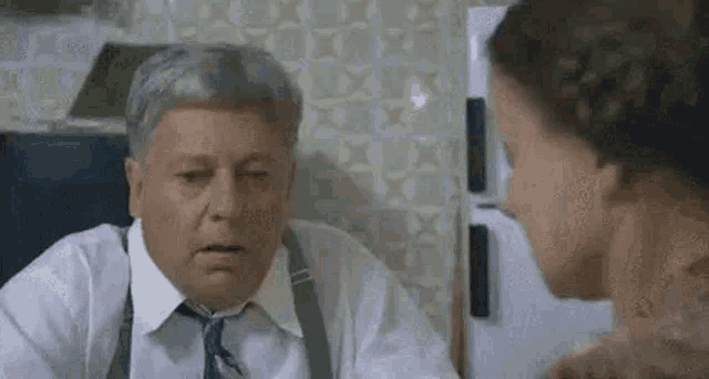 a man and a woman are talking to each other in a kitchen .