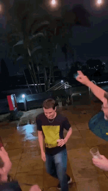a man wearing a black shirt with a yellow stripe on it is dancing