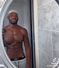 a shirtless man is taking a picture of himself in the mirror .