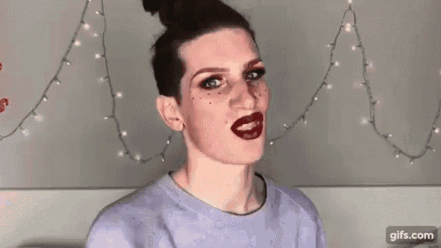 a young man with makeup on his face and red lipstick is making a funny face .