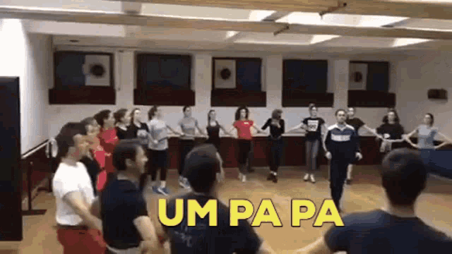 a group of people are dancing in a room with the word um pa pa in yellow letters .