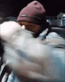 a man wearing a purple beanie and a mask is holding a bag .