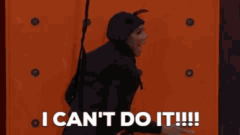 a woman in a devil costume is standing in front of an orange wall and saying `` i can 't do it ! ''