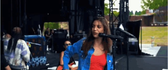 a woman in a red top is singing into a microphone on stage