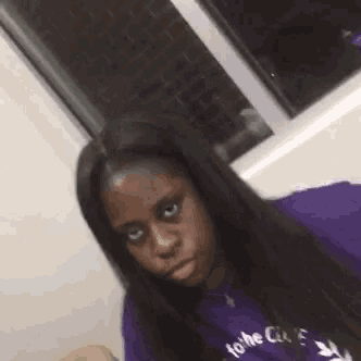 a woman is making a funny face while wearing a purple shirt .