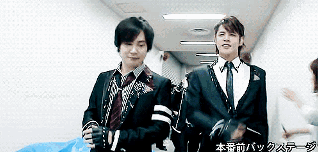 two men in suits are walking down a hallway with chinese writing on the bottom right