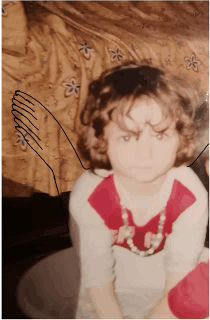 a little girl with curly hair is wearing a necklace