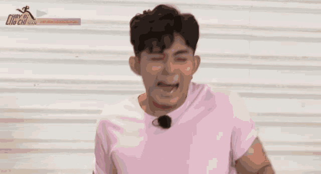 a man in a pink shirt is laughing with his hands in the air