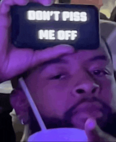 a man is holding a cell phone with the words `` do n't piss me off '' written on it .