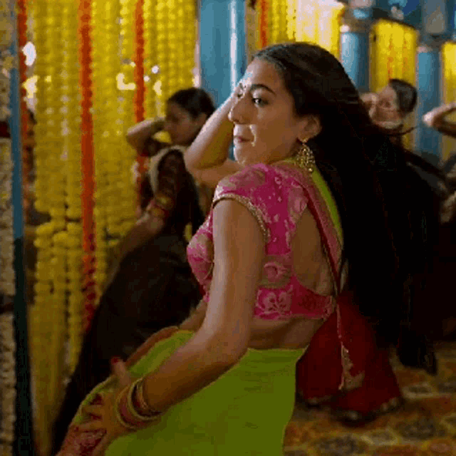 a woman in a green saree is dancing in a room