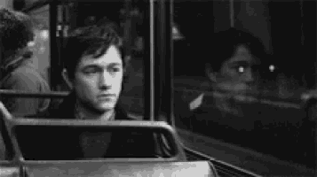 a man is sitting on a bus looking out of the window .