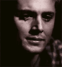 a close up of a man 's face with a tear running down his face .