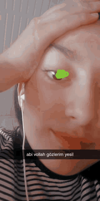 a woman wearing headphones has a green sticker on her eye