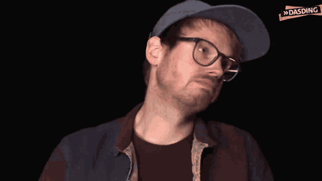 a man wearing glasses and a hat with the word dasding on the bottom right