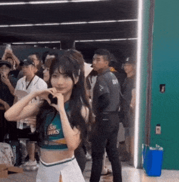a cheerleader is making a heart shape with her hands while standing in front of a crowd .