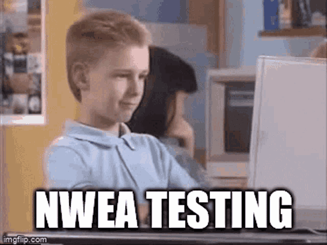 a young boy is sitting in front of a computer screen with the words " nwea testing " written on it .