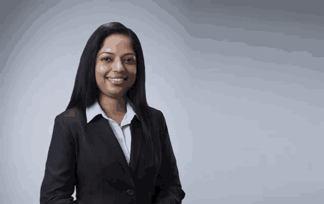 a woman in a business suit is smiling for the camera .