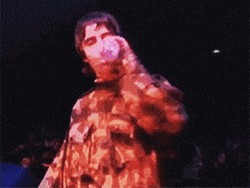 a man in a camo jacket is singing into a microphone in front of a crowd