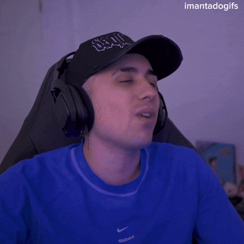 a man wearing headphones and a blue nike shirt waves his hand