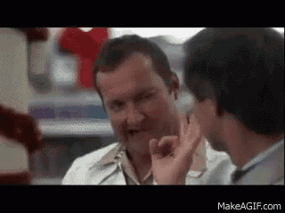 a man in a lab coat is talking to another man in a pharmacy .
