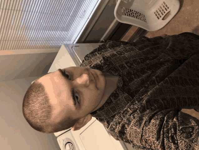 a man with a shaved head sits in front of a laundry machine